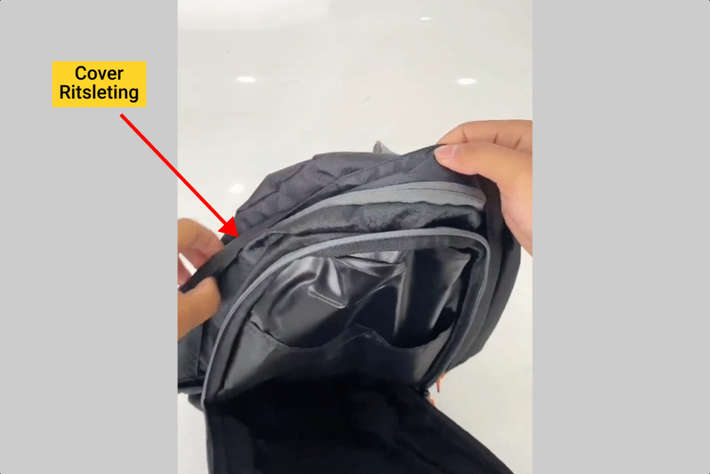 Tangan menunjukkan cover ritsleting kompartemen tas Inflico, text overlay āCover Ritsleting Agar Air Hujan Tidak Merembesā.