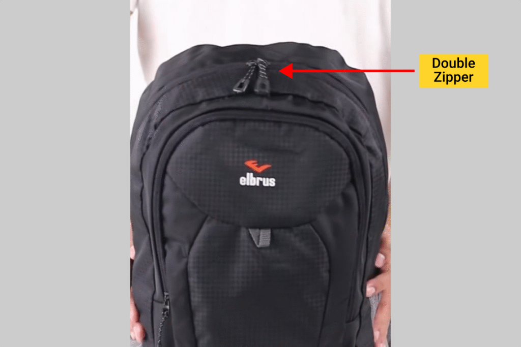 Tampak depan tas ransel Outvin TL 795 (Elbrus Detroid) warna hitam, tanda panah menunjukkan ritsleting kompartemen utama.